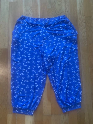 Blåa loungewear-byxor med bladmönster - Blåa loungewear-byxor från Cubus i storlek XL. Byxorna har ett vitt bladmönster över hela tyget och resår i midjan samt vid bensluten. Perfekta för chill dagar hemma. Materialet känns mjukt och stretchigt.