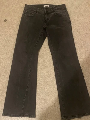 Svarta bootcut jeans - Säljer ett par svarta bootcut jeans med klassisk femficksdesign och flare. Jeansen har knapp- och dragkedjegylf samt detaljerade bakfickor. Perfekta för en avslappnad och trendig look. Det finns lite defekter med jeansen som jag har visat på bilderna❤️