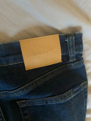 Mörkblå slim jeans från GANT - Snygga mörkblå jeans från GANT i modellen Hayes Slim. Klassisk femficksdesign med diskret GANT-logga på bakfickan och läderpatch i midjan. Jeansen har smal passform och är tillverkade i ett mjukt denimtyg som sitter riktigt bra.