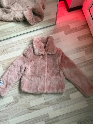 Fakepälsjacka  - Strl S. Rosa fakepälsjacka med två fickor i otroligt mjuk fuskpäls från märket Jakke  Nyskick men bör tvättas då den legat på vinden :) 