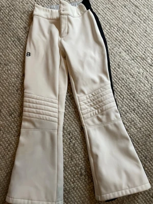 Vita skidbyxor från 8848 Altitude - Säljer ett par vita skidbyxor från 8848 Altitude med svarta detaljer på sidan. Byxorna har quiltade partier över knäna och är tillverkade i ett stretchigt material med mjuk fleece på insidan. Perfekta för vinterns alla äventyr i backen! Finns att hämta på Södermalm Medborgarplatsen, Slussen