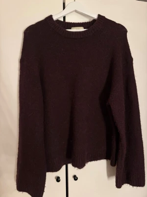 Vinröd tröja - Mysig vinröd teöja från Gina med rund halsringning och avslappnad passform. Tröjan har långa ärmar och ribbstickade detaljer vid hals, ärmslut och nederkant. Perfker skick och knappast använd!