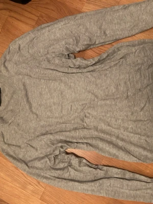 Ljusgrå basic tröja - En enkel och stilren ljusgrå tröja med rund hals och långa ärmar. Tröjan är tillverkad i ett mjukt och tunt material, perfekt för lager på lager. Passar till det mesta och har en klassisk, rak passform. Finstickad