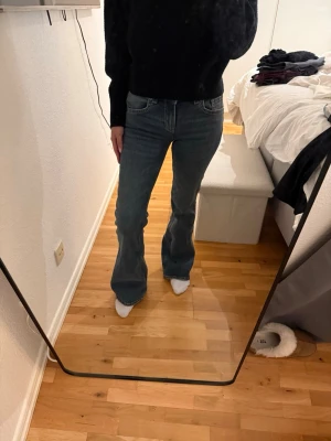 Blå bootcut jeans med hög midja - Säljer ett par blå bootcut jeans med hög midja och klassisk femficksdesign. Jeansen har en snygg tvätt och är tillverkade i ett stretchigt denimtyg som sitter bekvämt. Perfekta för dig som gillar en retroinspirerad look.