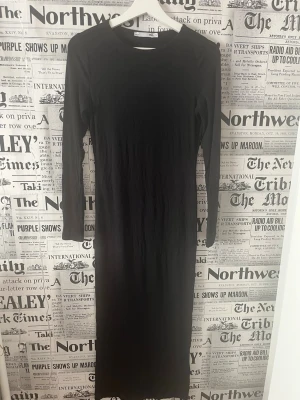 Svart långärmad ribbad klänning 157 - Säljer en svart långklänning från 157 med ribbad struktur. Klänningen har lång ärm och rund halsringning, perfekt för dig som gillar en enkel och stilren look. Passformen är normal och materialet känns mjukt och stretchigt. Den är ca 123cm lång från hals till slut jag är 163 och den går ner till mina anklar, måttet kan ni även se på bilderna 