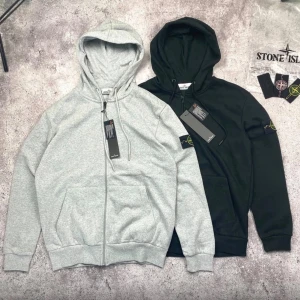 Stone Island ziphoodie svart & grå - (Finns i XS-S-M-L-XL)Två stilrena ziphoodies från Stone Island, en i svart och en i ljusgrå. Klassisk hoodie med dragkedja, huva med dragsko och fickor framtill. Ikonisk Stone Island-patch på vänster ärm. Perfekt för en avslappnad streetwear-look.