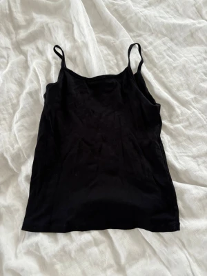 Svart linnetopp med smala axelband - Enkel och stilren svart linnetopp med smala axelband. Toppen har rak passform och är tillverkad i mjukt bomullsmaterial, perfekt för varma dagar eller som lager under andra plagg.💓💓