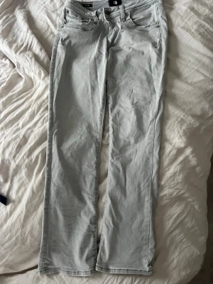 Ljusgrå raka jeans från LTB - Säljer ett par ljusgrå jeans från LTB med raka ben och klassisk femficksmodell. Jeansen har silverfärgade nitar och knapp, samt diskreta sömmar. Perfekta för en clean och stilren look. Extra knapp i midjan så att de blir mindre, går att ta bort