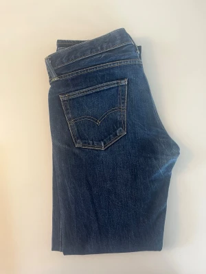 Mörkblå raka jeans från Levi's 511 - Snygga mörkblå jeans från Levi's med klassisk femficksdesign och raka ben. Jeansen har kontrastsömmar och är tillverkade i slitstark denim. Perfekta för en avslappnad och trendig stil.