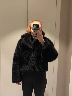 Svart fuskpälsjacka med krage - Säljer en svart pälsjacka som är hyfsat tunn. Funkar både till våren, hösten och ibland vintern.  Det finns inga tecken på användning, den är i jättebra skick! Nypris 800kr. 