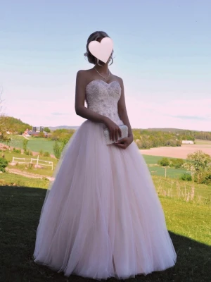 Ljusrosa Balklänning - Säljer min fantastiska ljusrosa balklänning i mycket fint skick (använd en gång).  • Passar ca storlek 32–36 tack vare snörning baktill • Hjärtformad urringning med pärl- och spetsdetaljer • Stor tyllkjol med prinsessvolym • Uppsydd i längd – jag är 160 cm och bar 10 cm klackar • Man får med en oanvänd underkjol för extra volym  Nypris: ca 9 000 kr Säljes för 6 000 kr 