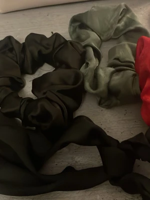 Fyra schrunchies - Säljer fyra stycken schrunchies helt oanvända. En röd, en grön, en svart, och en svart med hängande detalj.