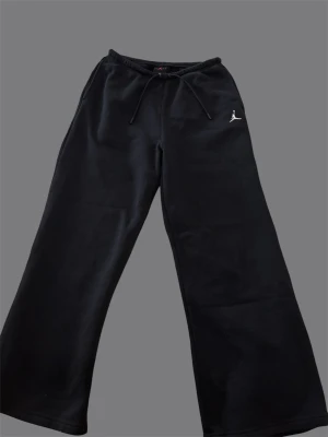 Svarta Jordan mjukisbyxor med brodyr - Säljer ett par svarta mjukisbyxor från Jordan med broderad logga på vänster ben. Byxorna har dragsko i midjan, raka ben och är gjorda i mjukt sweatshirtmaterial. Perfekta för chill dagar eller när du vill ha en sportig look.