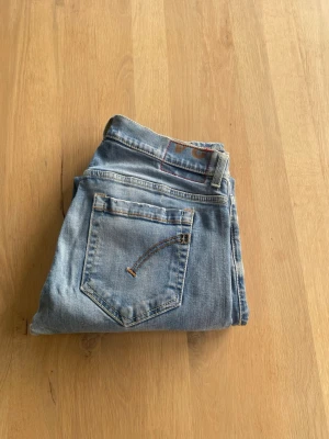 Dondup jeans - Snygga Blåa jeans från Dondup med klassisk femficksdesign och en slim passform. Jeansen har en diskret tvättad look med snygga slitningar och är tillverkade i stretchigt denim för en bekväm passform. Perfekta för en stilren och modern look.
