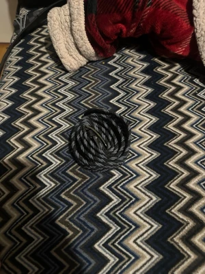 Svart flätat bälte i syntet - Snyggt svart flätat bälte i syntetmaterial. Bältet har en enkel metallspänne och passar perfekt till jeans eller byxor för en stilren look. Flätad design ger en cool och modern känsla.