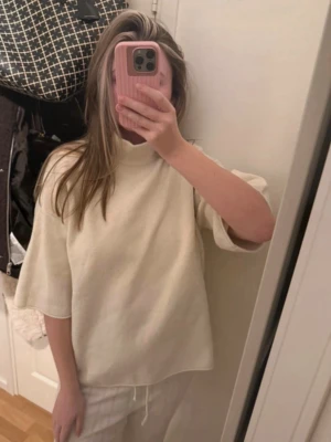 Vit oversized tröja med halv polo - En enkel och stilren vit tröja med halv polokrage och lös passform. Tröjan har halvlånga ärmar och är gjord i ett mjukt, tjockare material som känns skönt mot huden. Perfekt för en avslappnad och trendig look.