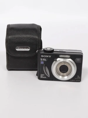 Sony digitalkamera svart - Kompakt digitalkamera från Sony, med 5.1 megapixlar. Kameran är svart med silverfärgad linsring och har en stor display på baksidan. Medföljer gör ett svart fodral i läderimitation. Kameran är funktionstestad och fungerar! Skulle man ångra sig så får man givetvis lov att retunera inom 48 timmar men returkostnaderna står köparen för själv