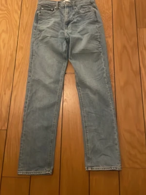 Ljusblå raka jeans från Jack & Jones  - Klassiska ljusblå jeans från Jack & Jones med rak passform och hög midja. Jeansen har fem fickor, bälteshällor och en patch bak i midjan. Tillverkade i slitstark denim, perfekta för en avslappnad och trendig look. Storlek längd 32 och midjemått 28