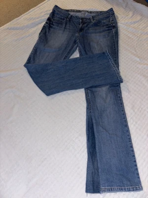Lågmidjade jeans - Snygga blå bootcut jeans från Esprit med klassisk femficksdesign och broderade bakfickor. Jeansen har en lätt tvättad look och är tillverkade i denim med en skön passform. Innerbenslängd: 83 cm, midjemått: 41 cm rakt över