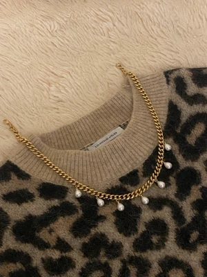 Guldfärgat halsband med pärlor - Stilrent halsband i guldfärgad rostfritt med kedja och sju hängande vita pärlor. Perfekt accessoar för att lyfta din outfit med en trendig och elegant touch.