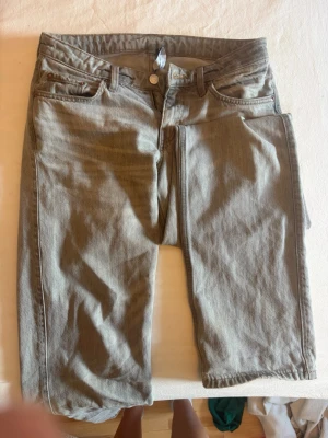 Ljusgrå jeans från weekday i stilen Arrow - Snygga ljusgrå jeans från Weekday med klassisk femficksdesign och raka ben. Jeansen har knapp- och dragkedjegylf samt bälteshällor. Perfekta för en avslappnad och stilren look.