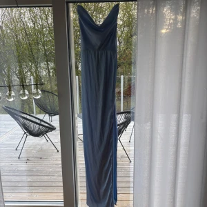 Ljusblå långklänning med slits - Säljer en elegant ljusblå långklänning med smala axelband och v-ringad halsringning. Klänningen har en snygg slits framtill och öppen rygg med tunna band. Perfekt för speciella tillfällen där du vill känna dig extra fin. Köpt för 899kr hos Nelly 2024 och använt endast en gång. Inget fel på den alls. Storlek 40, lite liten i storleken. 