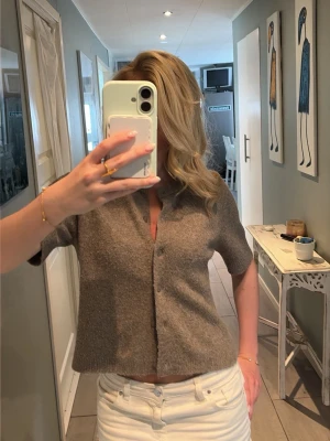 Kortärmad beige kofta från Kappahl  - Kortärmad kofta i beige, mjukt stickat material med knappar framtill. 