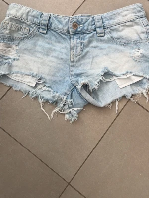 Lågmidjade jeansshorts - Lågmidjade jeansshorts från gina tricot i st M 14+ är i jättebra skick förutom att det egentligen skulle varit med pärlor vid fickorna, som tyvärr har ramlat av efter några gånger, annars är dem i superbra skick och har använt fåtal gånger💞