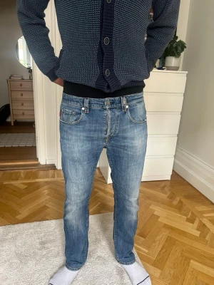 Blå Tramarossa  jeans med raka ben - Säljer ett par klassiska blå Tramarossa jeans med raka ben och fem fickor. Jeansen har en snygg tvättad look och detaljer som röda Levi's-tag på bakfickan. Perfekt för dig som gillar tidlös stil och vill ha ett par jeans som funkar till allt.