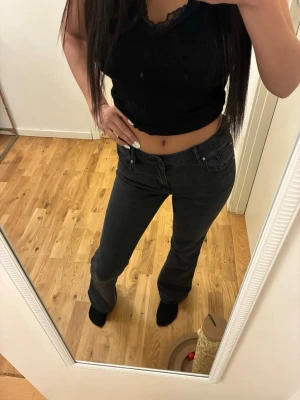 Mörkgråa bootcut jeans med låg midja - Snygga Mörkgråa bootcut jeans med låg midja,  klassisk femficksdesign och två fickor där bak.  Jeansen har en tight passform upptill och utsvängda ben nertill. Från lager 157 i storlek 150cm. Använda ett fåtal gånger därav mycket bra skick. 