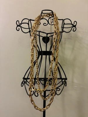 Långa guldpläterat kedjehalsband - Säljer långa halsband i guldpläterad metall med flera lager av kedjor i olika tjocklekar och länkar. Halsbandet har en chunky och trendig look som verkligen sticker ut. 