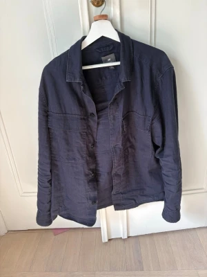 Overshirt skjorta - Säljer en mörkblå skjorta  med klassisk krage och knappar framtill. Skjortan har två bröstfickor och är tillverkad i mjuk bomull. Perfekt för en avslappnad och stilren look. Storlek M passar mig som är 183cm
