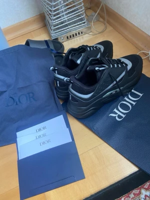 Svarta sneakers med reflex detaljer - Säljer ett par helt nya svarta sneakers med vita och reflekterande detaljer. Skorna har en chunky sula, meshpaneler och läderdetaljer. 