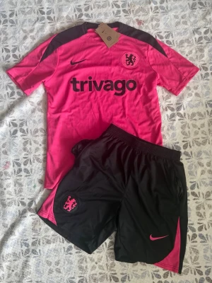 Chelsea träningsset rosa/svart Nike - Chelsea fotbollsträningsset i storlek S. Shortsen har fickor med dragkedjor. Helt nya och oanvända, perfekt till sommaren. Hör gärna av vid frågor!