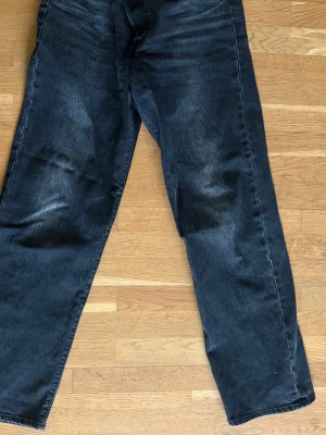 Levi's Ribcage Straight Ankle jeans - Säljer ett par svarta Levi's Ribcage Straight Ankle jeans med rak passform och hög midja. Jeansen har klassisk femficksdesign och är tillverkade i denim. Storlek 29/31. Sparsamt använda. Nypris 1000 kr