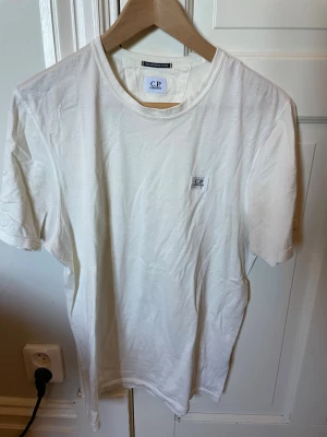 Vit t-shirt från C.P. Company - Snygg vit t-shirt från C.P. Company i 100% merceriserad bomull. Klassisk passform med rund halsringning och diskret logotyp på bröstet. Perfekt basplagg med stilren look. Köpt på NK herrtrend Göteborg 