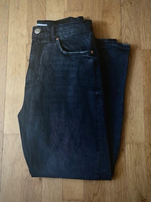 Straight jeans high waisted - Jeans från Gina Tricot. Högmidjade jeans med fem fickor och hällor för bälte. Modellen har raka ben. Gylf med dragkedja och knapp i metall framtill. Innerbenslängd: 69 cm.