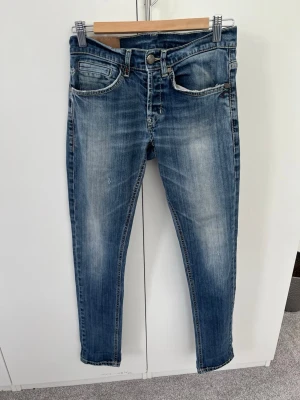 Blå slim fit jeans från Dondup - Snygga blå slim fit jeans från DunDop med klassisk femficksmodell och slitna detaljer. Jeansen har en tvättad look med ljusare partier och kontrastsömmar. Tillverkade i bomull med stretch för extra komfort.