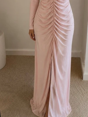 Viral blush pink ruched maxiklänning ✨🌸 -  Helt ny blush pink/maxiklänning med draperad ruched design som ger en lyxig och smickrande silhuett. Stretchigt material med elegant fall som framhäver formerna på ett fantastiskt sätt.  Perfekt till fest, bröllop, examen, student, middag, semester eller sommarens alla kommande event 💕  ✔ Helt ny ✔ Stretchig och bekväm ✔ Elegant slits framtill ✔ Trendig clean girl-look ✔ Snabb leverans  Säkra den inför sommarens fester och speciella tillfällen – svårt att