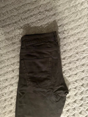Grå loose fit jeans från Jack & Jones - Snygga grå jeans från Jack & Jones i loose fit-modell. Klassisk femficksdesign med knappgylf och bälteshällor. Perfekta för en avslappnad och trendig stil. Materialet är mjukt och bekvämt, vilket gör dem lätta att bära hela dagen.