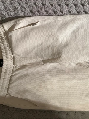 Vita slim fit mjukisbyxor H&M - Snygga vita mjukisbyxor från H&M i slim fit-modell. Byxorna har resår i midjan, sidofickor och är tillverkade i ett mjukt och bekvämt material. Perfekta för en avslappnad och stilren look.