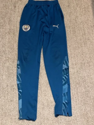 Blåa tränings kläder med ett lag och ett märke på - Blåa tränings kläder för vintern och det håller dig varm. De är sköna fast inte baggie och det är för fotboll. Använd fast det märks inte att den är använd och det finns ett märke på byxorna vid knät men ingen kommer märka det när du spelar eller har på dig det. De är fina och väldigt nice.