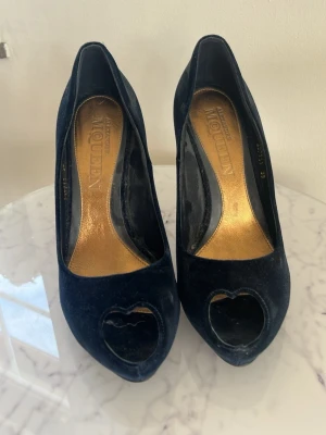 Alexander McQueen blå sammet pumps med hjärtan – storlek 39 + originalbox - Säljer superfina Alexander McQueen peep toe pumps i mörkblå sammet med signatur hjärtformad tå! Använda endast 1 gång och i jättebra skick. ✨ Allt ingår: originalbox. Klassisk statement-modell perfekt till fest och fin styling. Nypris runt 5000+ kr. Frågor? Skriv gärna! Kan skickas snabbt 😊