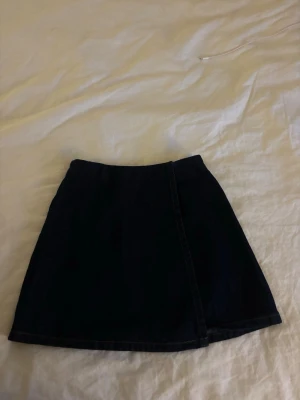 Mörkblå jeanskjol från Carin Wester - Snygg svart jeanskjol från Carin Wester med rak passform och dragkedja bak. Kjolen är kort och har en stilren design som passar till många olika looks.