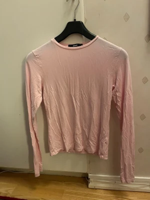 Ljusrosa långärmad topp från BikBok - Säljer en ljusrosa långärmad topp från BikBok. Modellen är enkel med rund halsringning och smal/tight passform. Materialet är mjukt och strechigt.