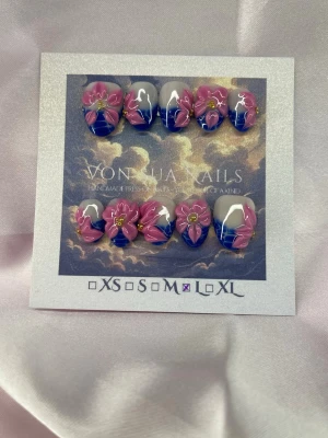 Yemoja (L);ExtraShortAlmond  - Unika handgjorda press-on naglar i storlek L: 17 mm, 12,5 mm, 13 mm, 12 mm, 10 mm . Naglarna har en cool blå tipp med 3D-blommor i rosa och guid. Formen är extra kort mandel. Perfekt för dig som vill ha något extra till naglarna!