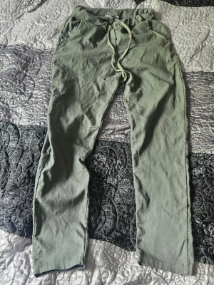 Gröna linnebyxor med dragsko - Snygga gröna linnebyxor med raka ben och bekväm resårmidja med dragsko. Byxorna har sidfickor och är tillverkade i ett luftigt linnematerial som passar perfekt för en avslappnad stil. Perfekta för dig som gillar en chill och enkel look.