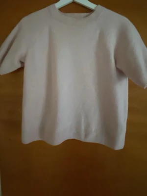 Ljusrosa stickad tröja kort ärm från H&M - Söt ljusrosa stickad tröja i cash med korta ärmar och rund hals. Tröjan har en enkel och clean design utan synliga detaljer eller mönster.Den har blivit lite mindre i tvätten❣️
