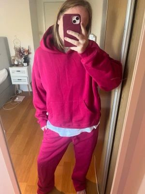 Mysigt mörkrosa loungewear-set - Säljer ett mjukt och bekvämt loungewear-set i mörkrosa färg. Setet består av en hoodie med känguruficka och matchande byxor med avslappnad passform. Perfekt för chill dagar hemma. Materialet känns fleeceliknande inuti och är riktigt skönt mot huden. Kan köpas som ett set eller separat!