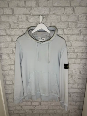 Stone Island hoodie - Stone Island hoodie i ljusblå färg. Riktigt clean och ovanlig färg som sticker ut snyggt. Tröjan är i fint skick överlag med endast lätt missfärgning runt luvans kant, inget som syns mycket vid användning.